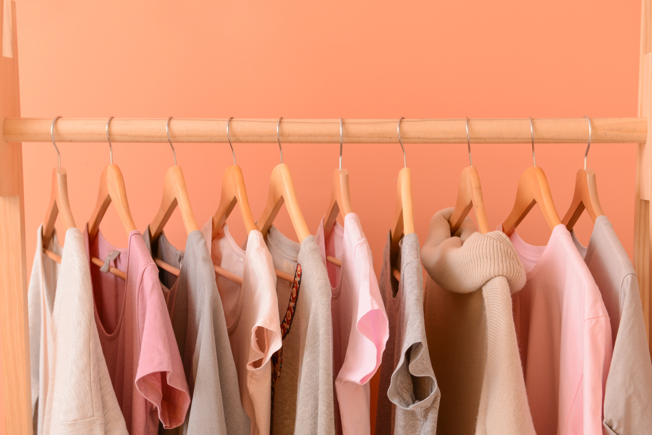 Rack with Hanging Clothes on Color Background